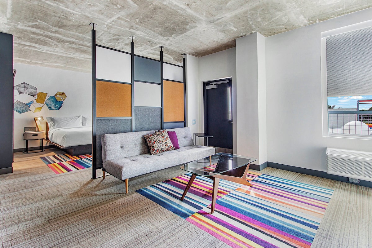 A modern living room with a sofa, coffee table, and colorful striped rug.
