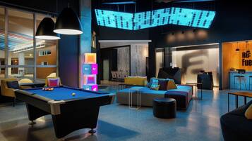 A modern lounge area with a pool table, comfortable seating, and ambient lighting.