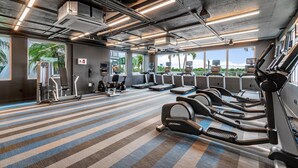 Un gimnasio con cintas de correr, máquinas elípticas y equipo de pesas.