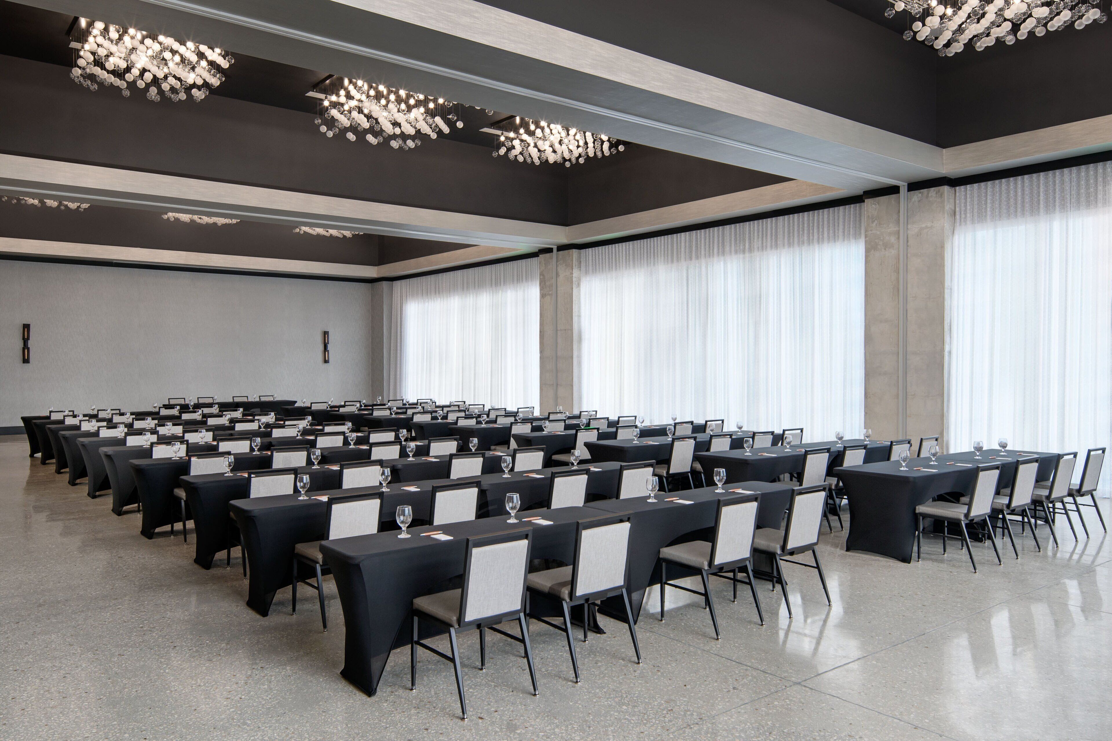 A conference room with rows of tables, chairs, and nameplates, equipped with wine glasses.