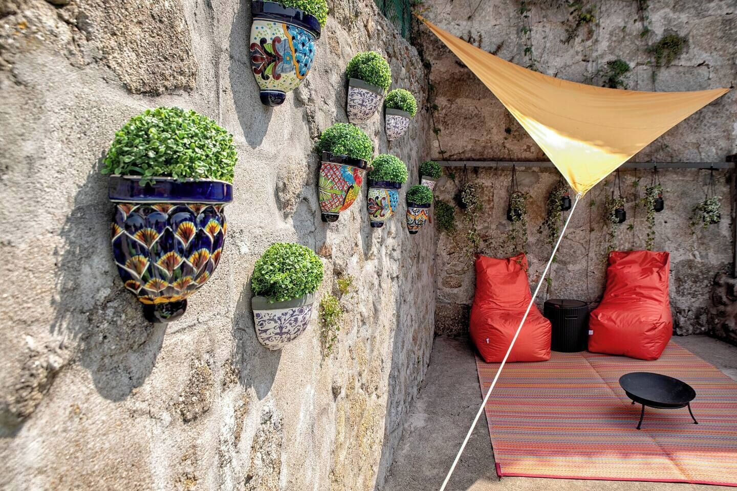 A stone wall with multiple colorful planters and a yellow canopy.