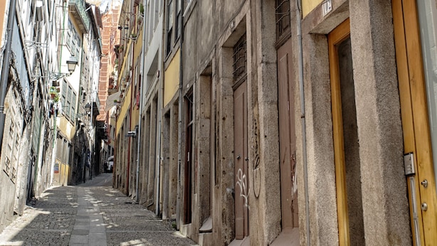Una estrecha calle adoquinada flanqueada por edificios históricos, con balcones y puertas de madera.