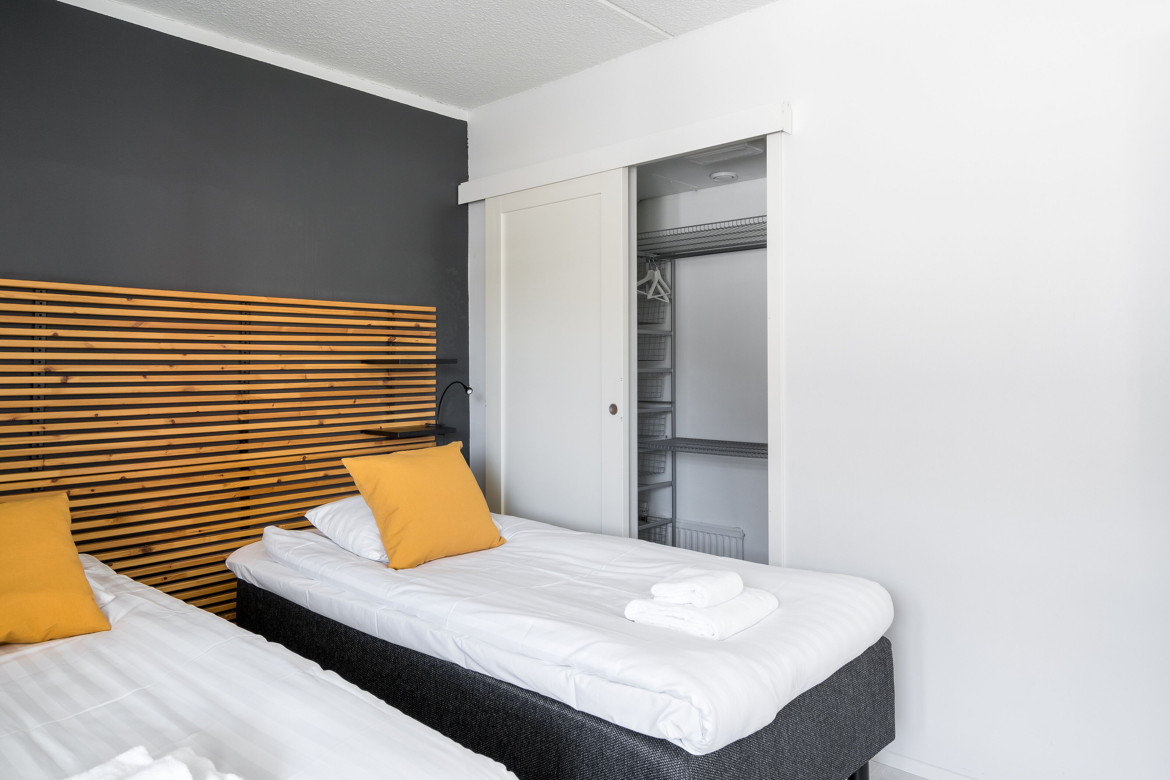 A hotel room with two beds, a wardrobe, and a walk-in closet.