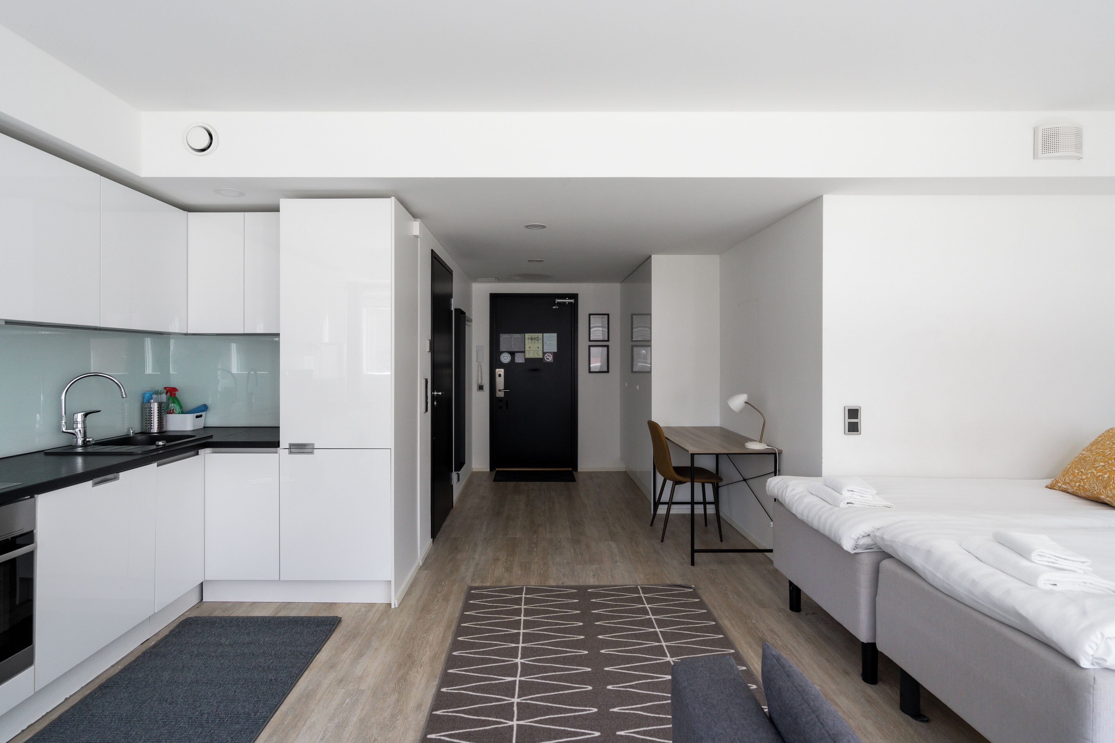 Habitació d'hotel compacta amb cuineta, zona de dinar i llit.