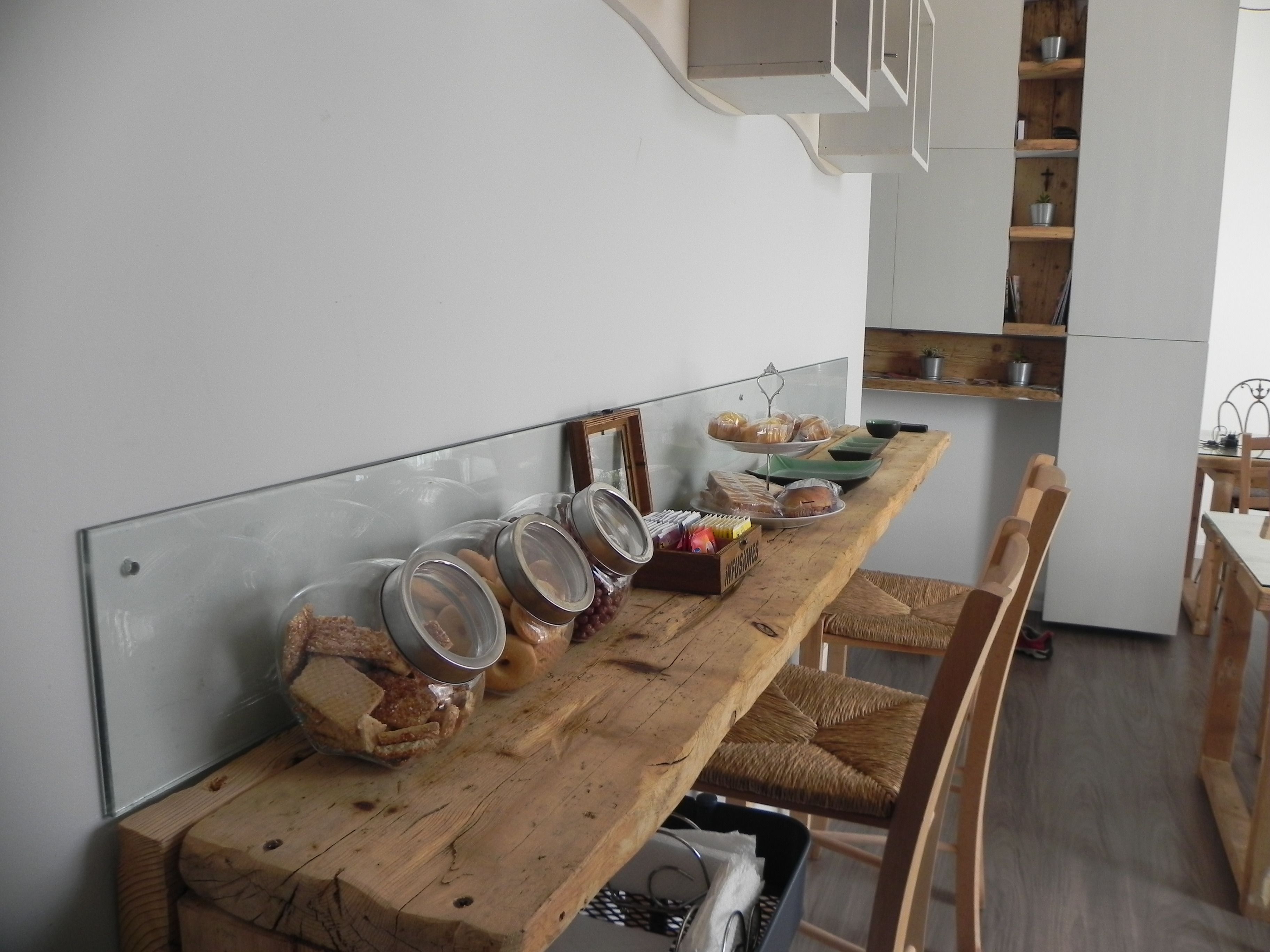 A kitchen with a wooden countertop, jars, and a bread display.