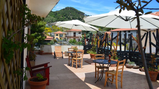 An outdoor patio with wooden tables and chairs, white umbrellas, and potted plants. - Gea apartment Etna (Nicolosi)
