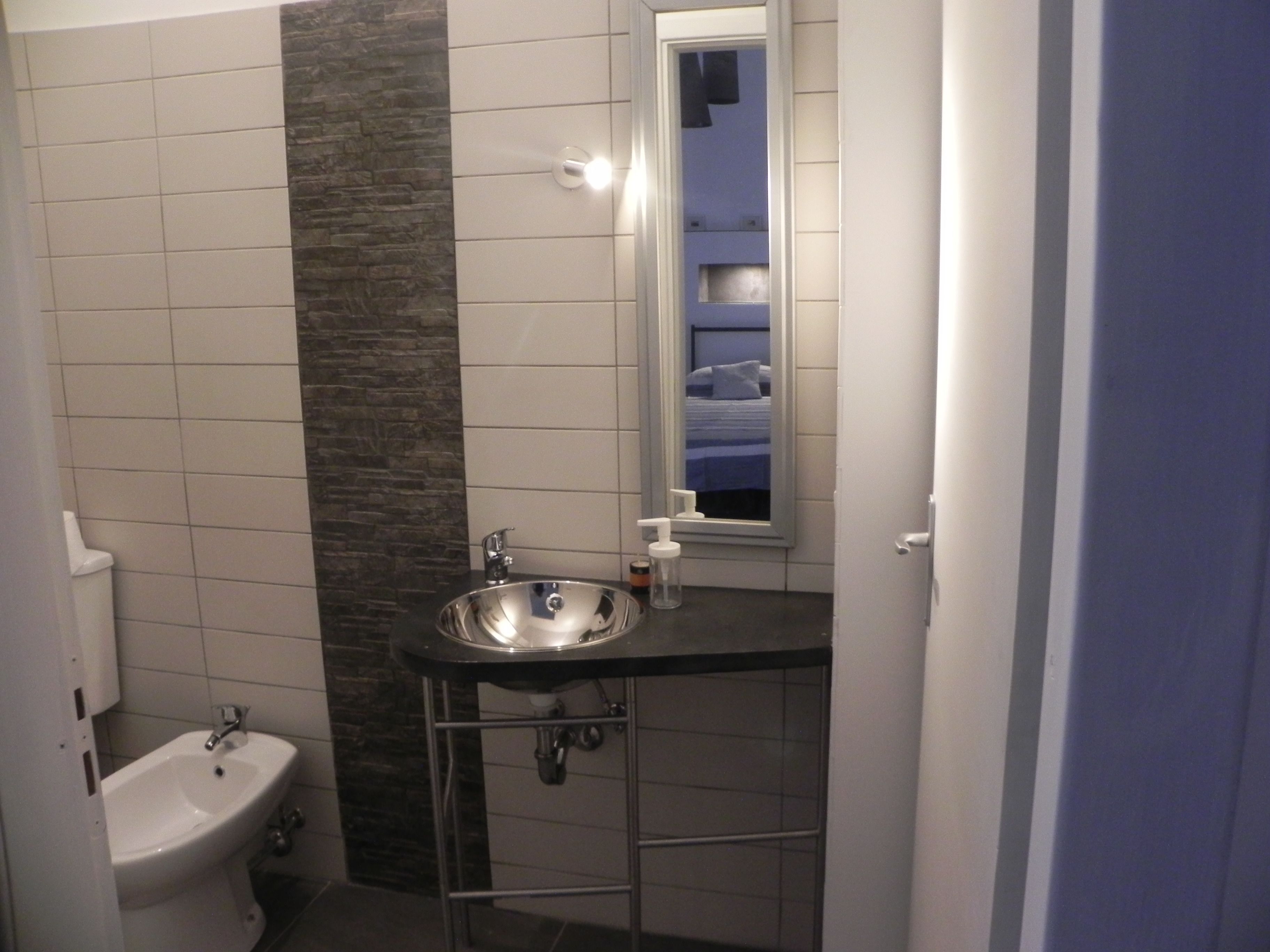 A bathroom with a white sink, a mirror, and a window.