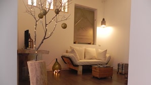 A cozy living room with a wooden floor, a sofa, a coffee table, and a decorative tree. - Gea apartment Etna (Nicolosi)