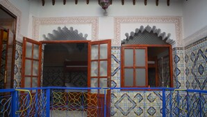 Habitació tradicional amb treballs de rajola ornamentals, un balcó de fusta amb baranes blaves i un sostre decoratiu.