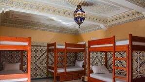 Una habitació amb quatre llits superposats de fusta, un mur amb rajoles estampades i un sostre decoratiu.