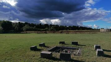 Un campo cubierto de hierba con un hoyo para fogatas rodeado de bloques de piedra.