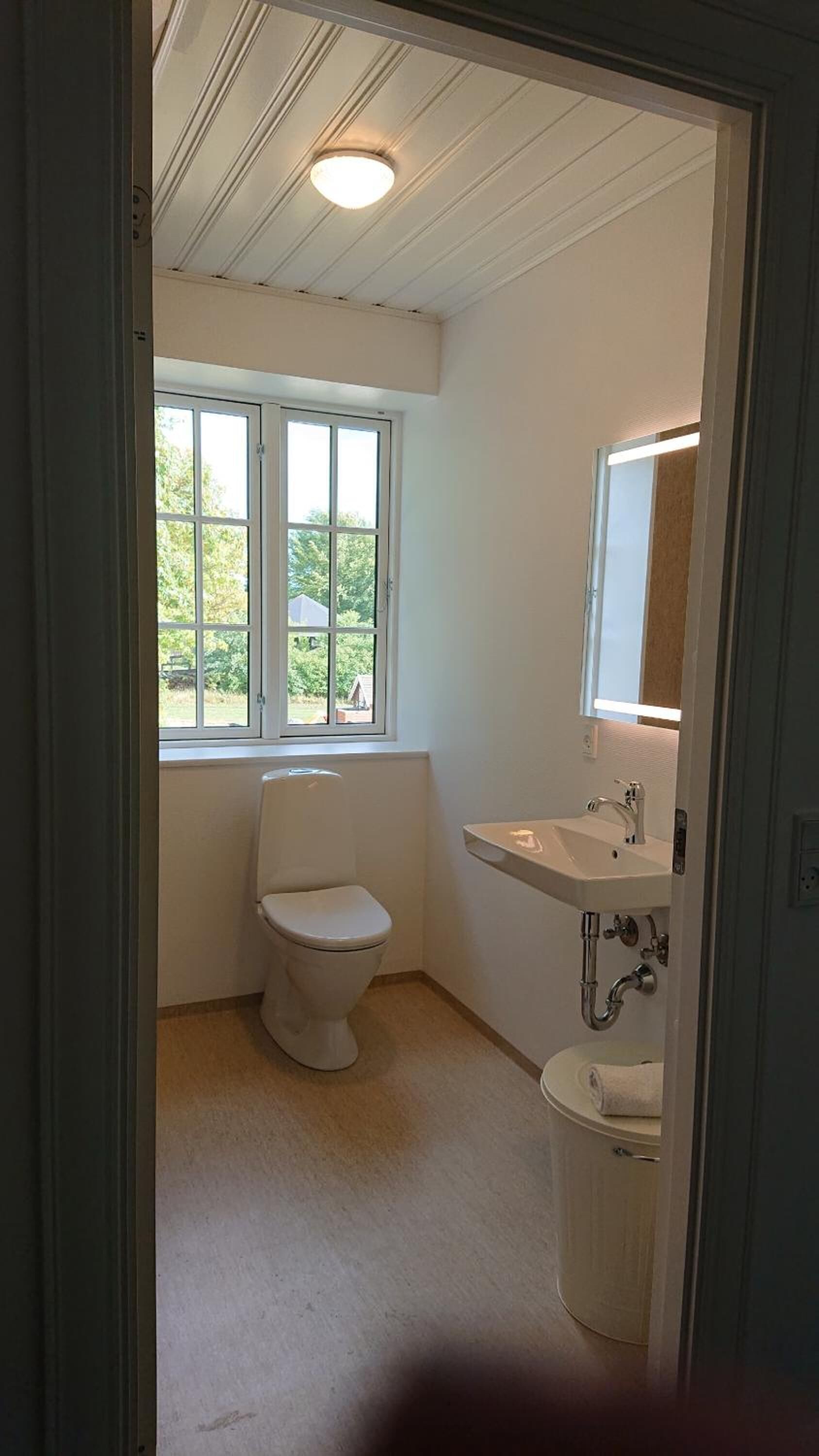 A small, clean bathroom with a toilet, sink, and window.