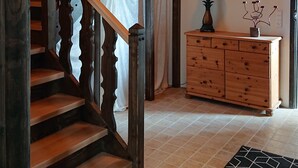 Una escalera de madera con barandilla decorativa, un armario de madera y una alfombra estampada.