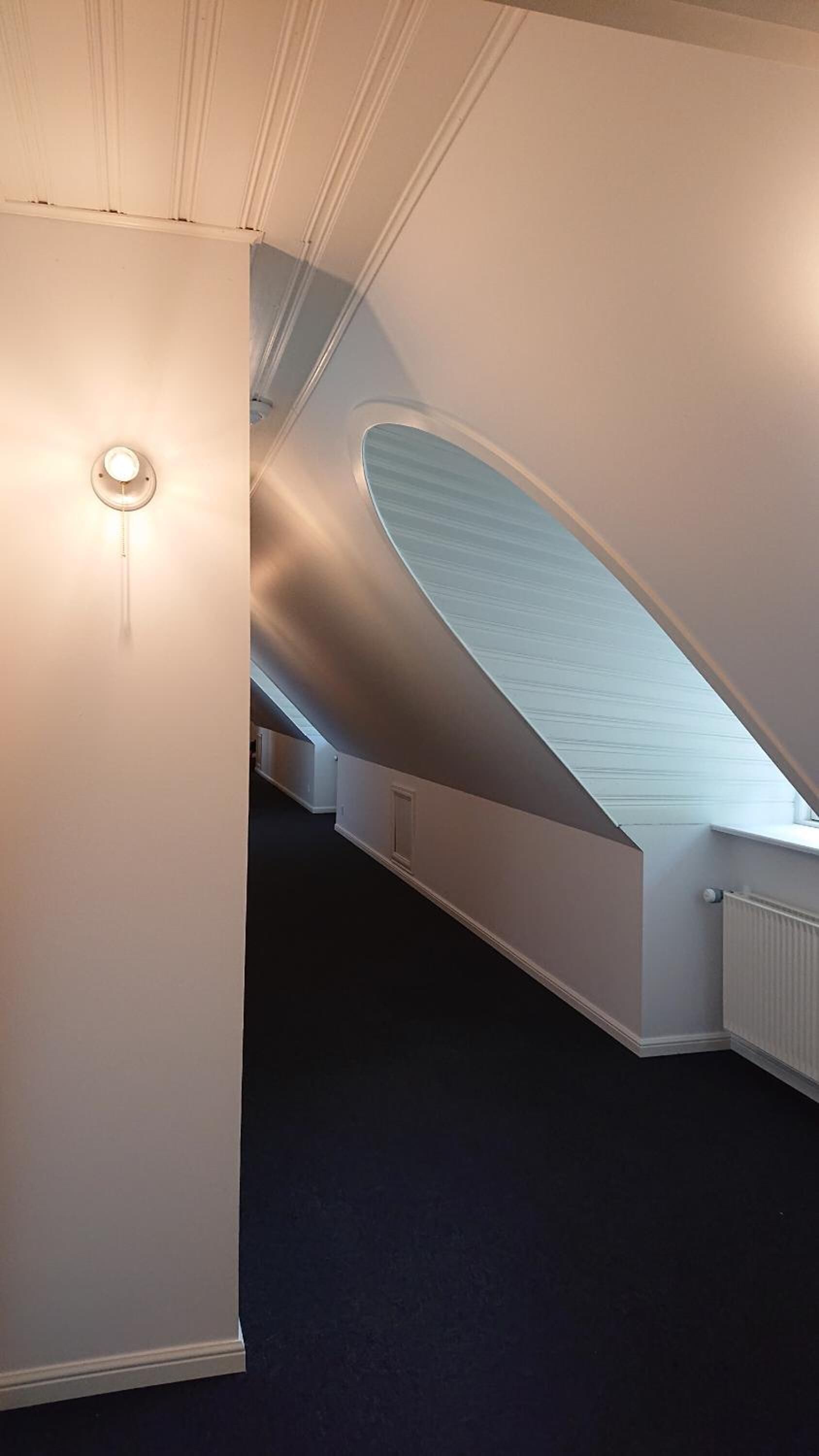 A modern interior with a curved ceiling and a central light fixture.