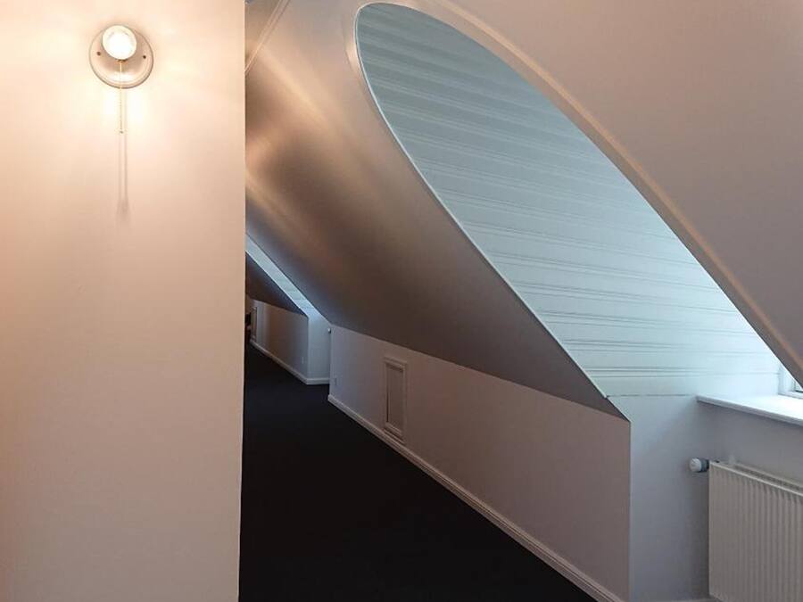 A modern interior with a curved ceiling and a central light fixture.