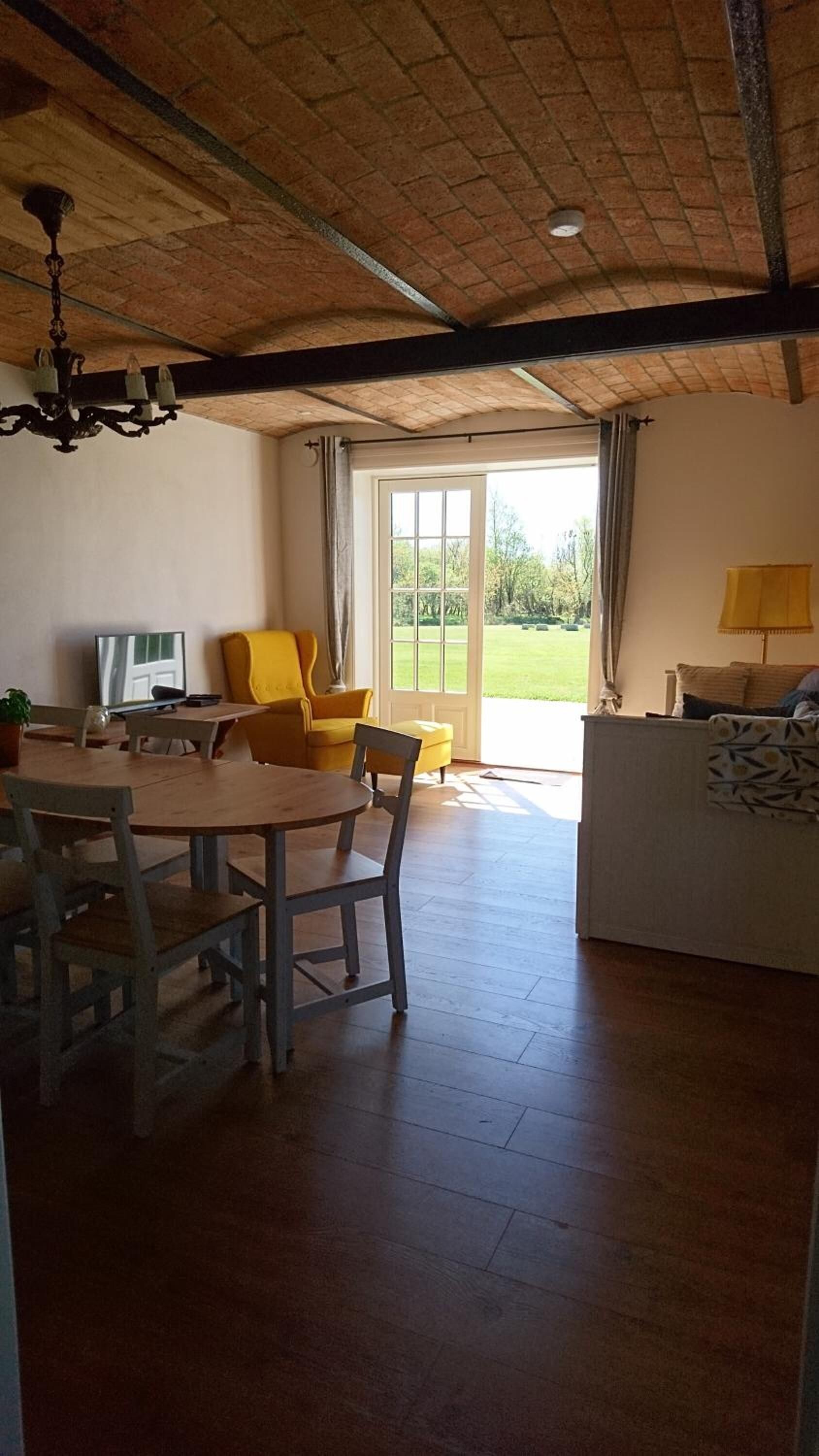 Un grand espace de vie comprenant une table à manger, des chaises jaunes, un canapé et un téléviseur.