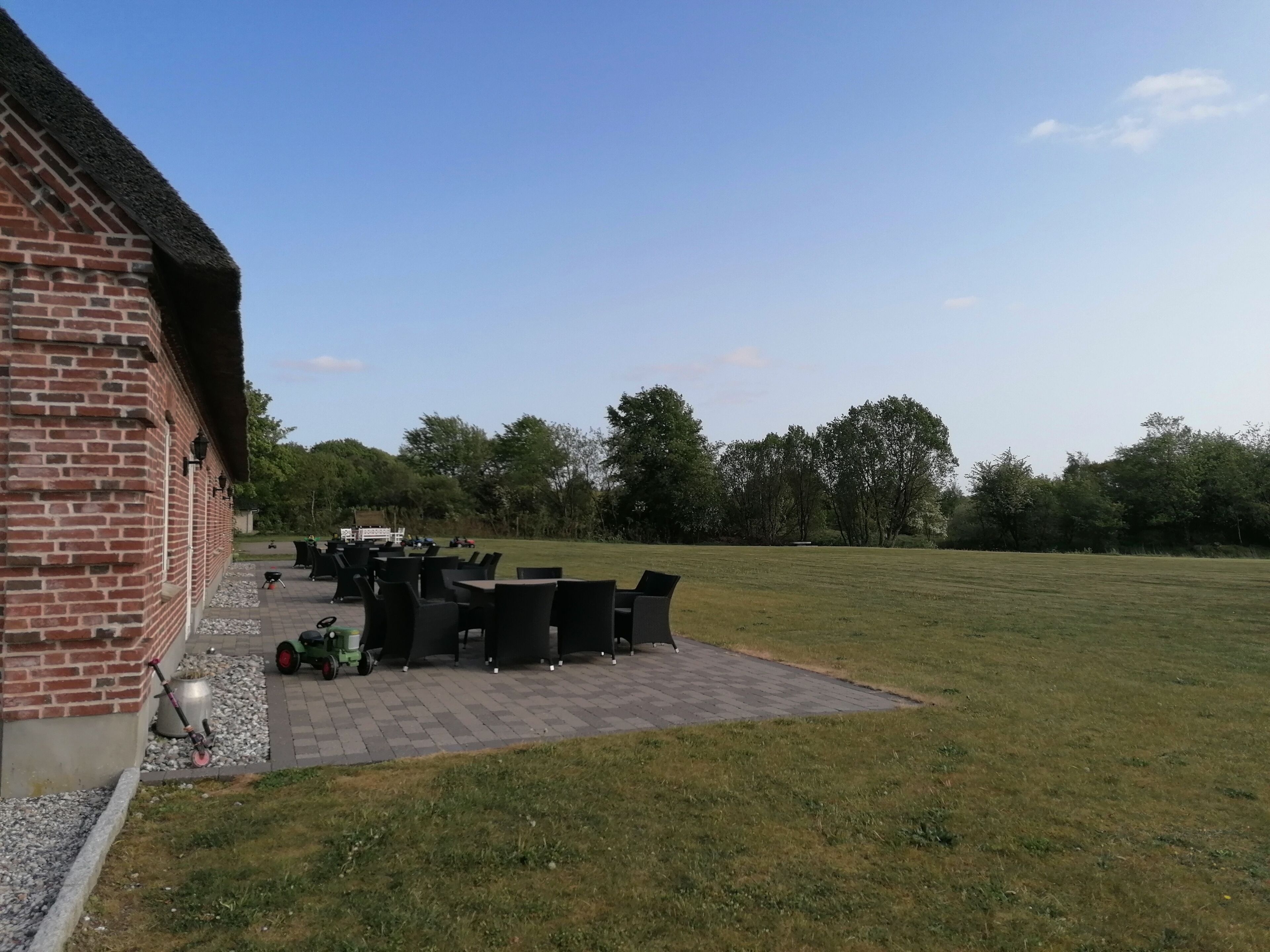 Een terras met tuinmeubilair, een bakstenen gebouw en een grasveld.