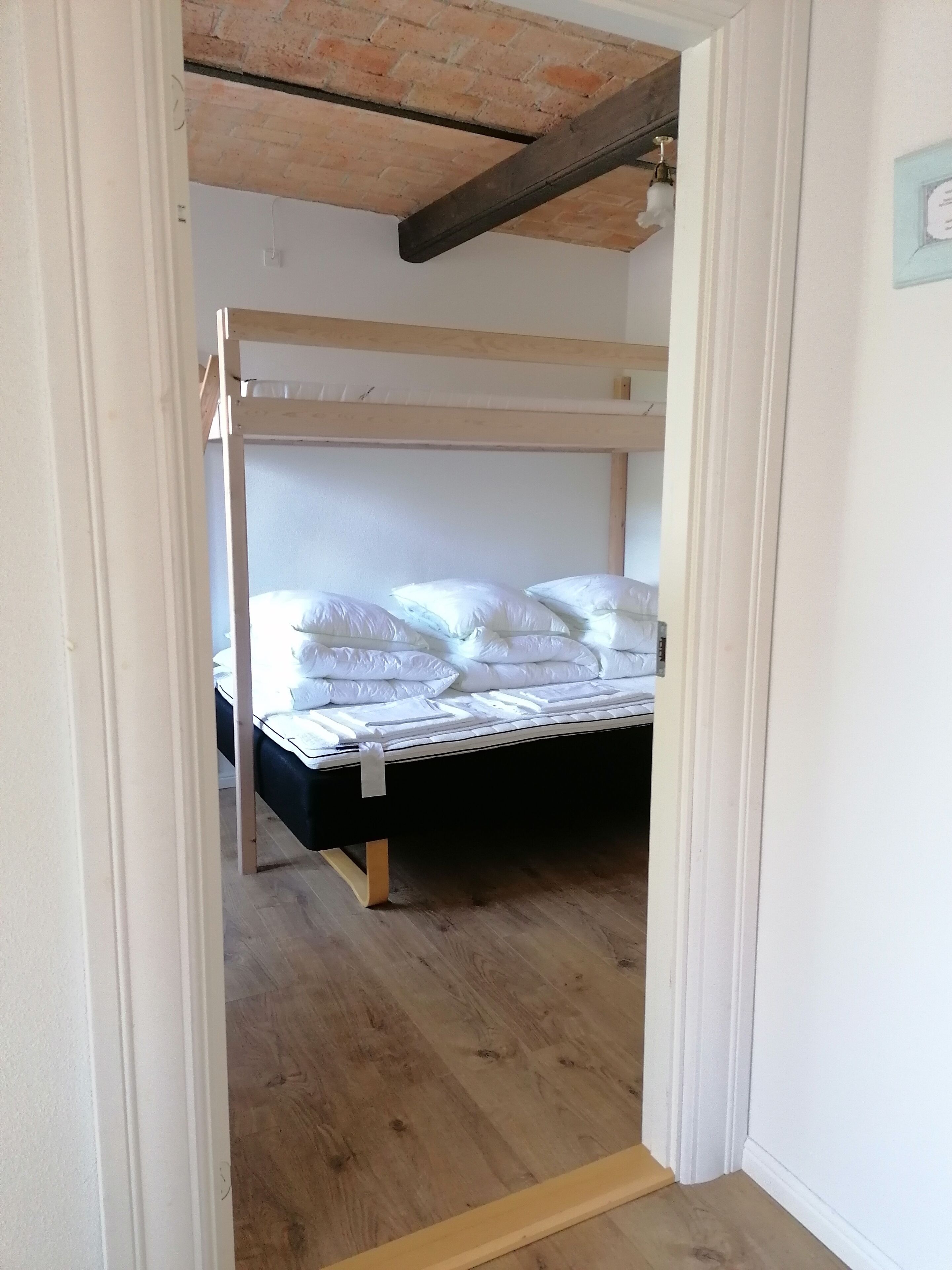 Una habitación con literas, suelo de madera y techo de ladrillo.