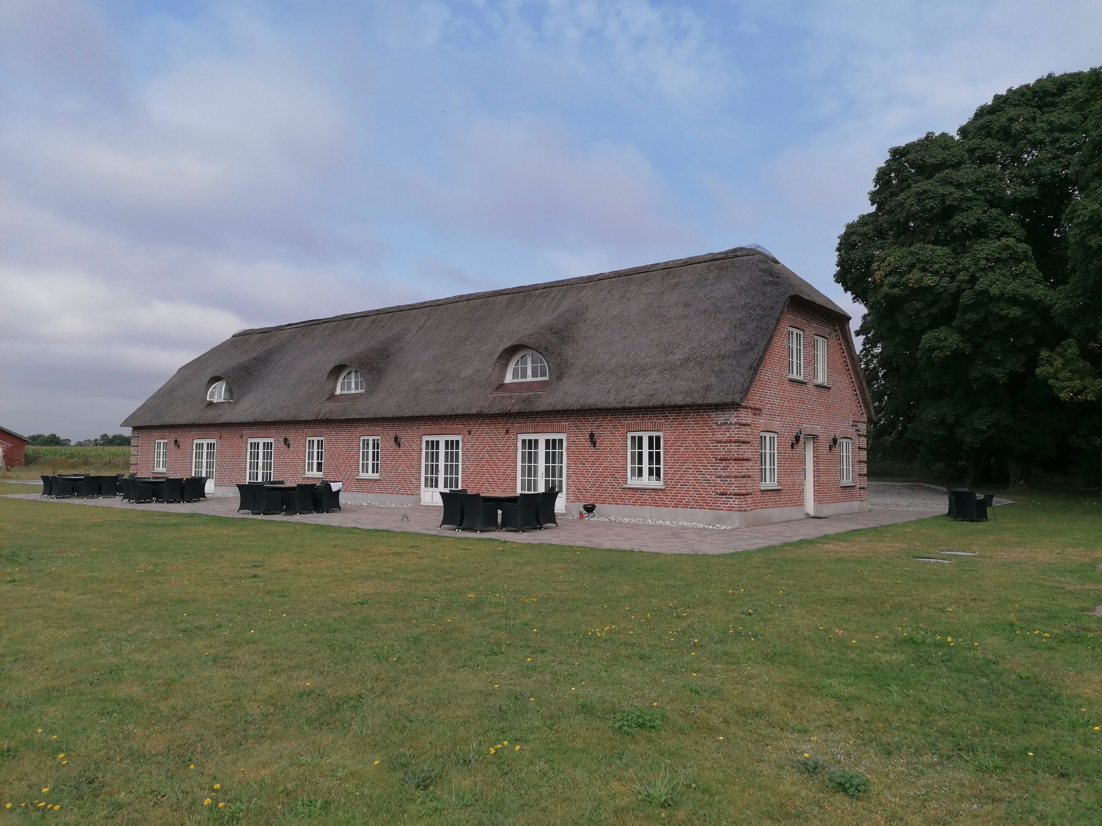 A brick building with a thatched roof, multiple windows, and outdoor seating.