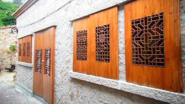 Edifici tradicional amb portes i finestres de fusta, parets de pedra i un camí de maó.