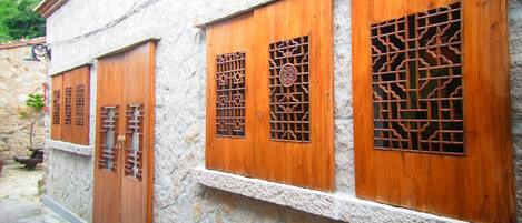 Un edificio tradicional con puertas y ventanas de madera, paredes de piedra y un camino de ladrillo.