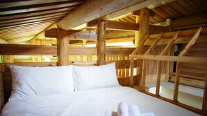 A wooden cabin bedroom with a bed, pillows, and rolled towels. - Mulight B&B (Nangan)