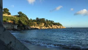 A coastal view with a concrete barrier, rocky cliffs, and a clear sky. - Mulight B&B (Nangan)