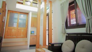 A room with a loft area, wooden furniture, a radiator, and a window with curtains. - Mulight B&B (Nangan)