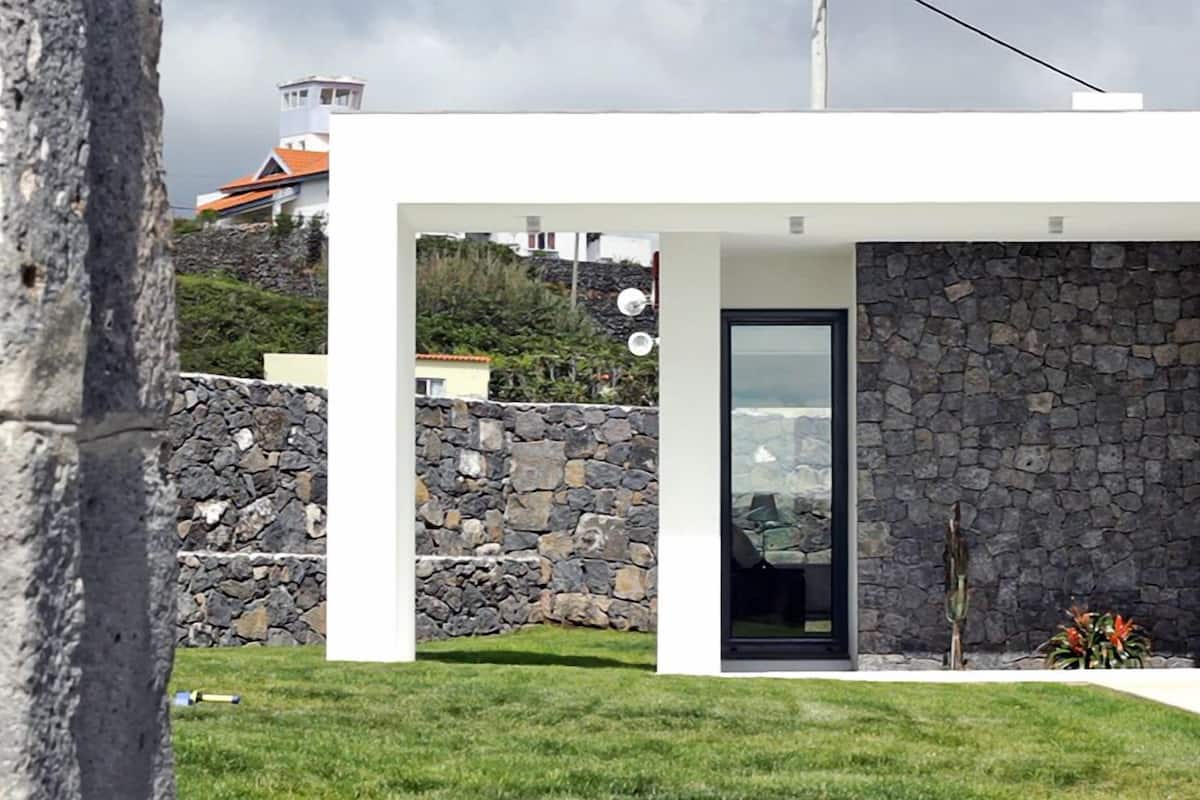 A modern house with a stone exterior, a glass door, and a view of the surrounding landscape.