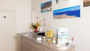 Una reception con un vaso di fiori, una caraffa di acqua al limone e brochure informative.