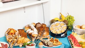 Un tavolo per buffet con diversi piatti, tra cui pasticceria, carni e frutta.