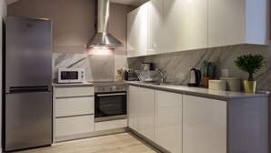 Una cocina moderna con electrodomésticos de acero inoxidable, armarios blancos y salpicadero de mármol.