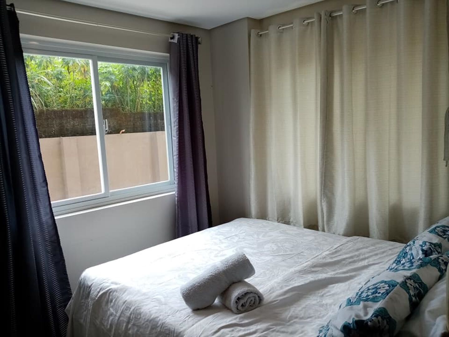 A bedroom with a bed, a window, and curtains.