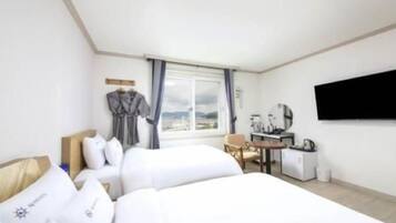 A hotel room with two beds, a desk, a chair, a TV, and a window with a view.