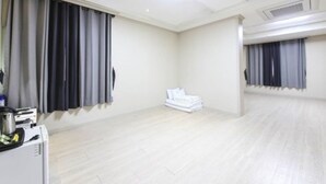 A spacious room with a large window, a flat-screen TV, and a stack of white towels. - MJ Tour Hostel (Yeosu)