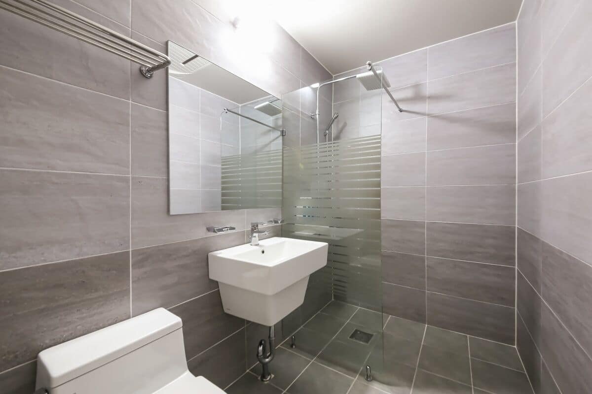 A modern bathroom with a glass shower enclosure, a white sink, and a toilet.