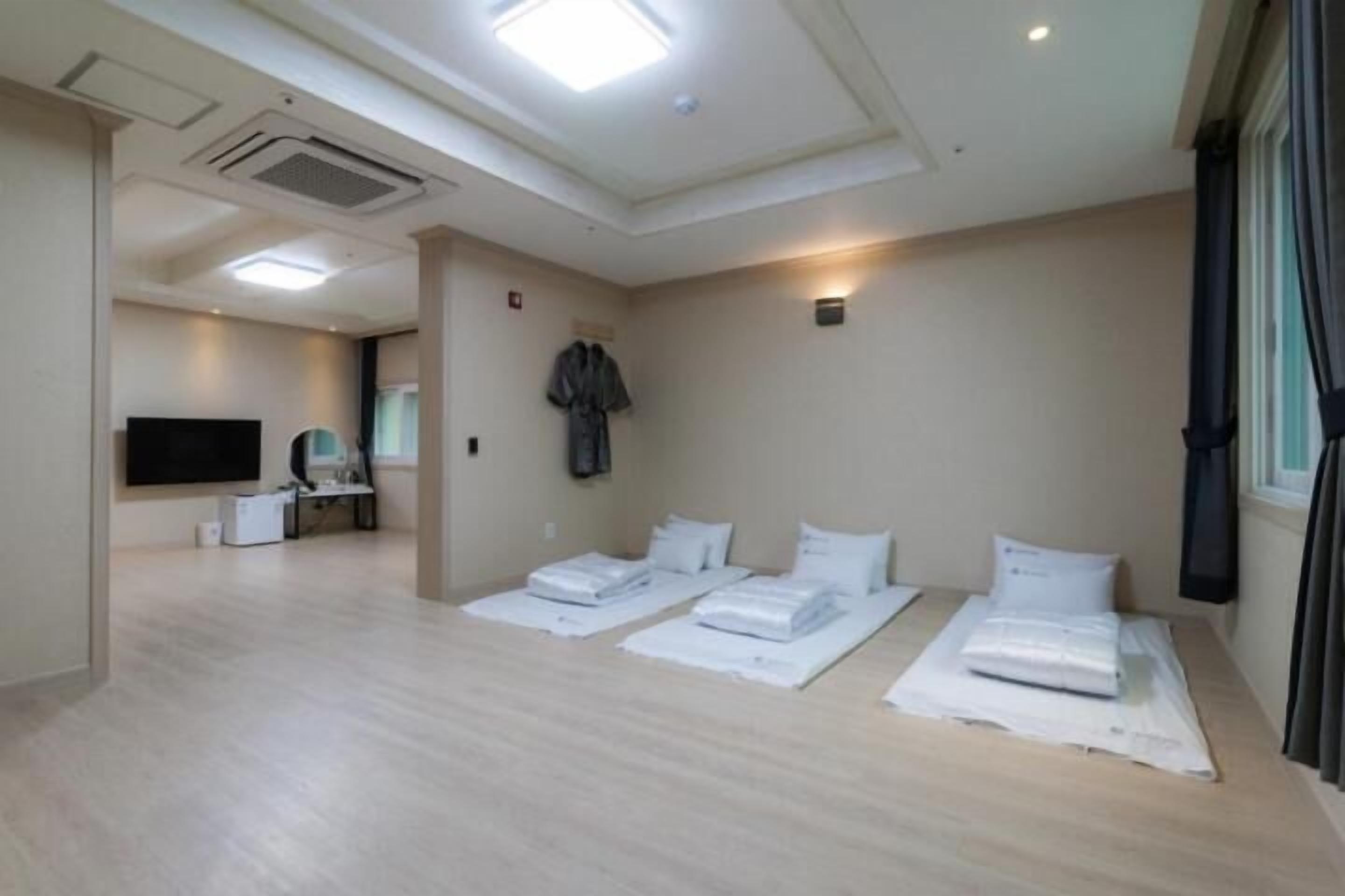 A hotel room with a flat-screen TV, a desk with a chair, and two beds with white linens.