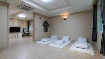 A hotel room with a flat-screen TV, a desk with a chair, and two beds with white linens.