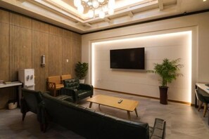 Un salon moderne avec un canapé, une table basse et un téléviseur à écran plat fixé au mur.