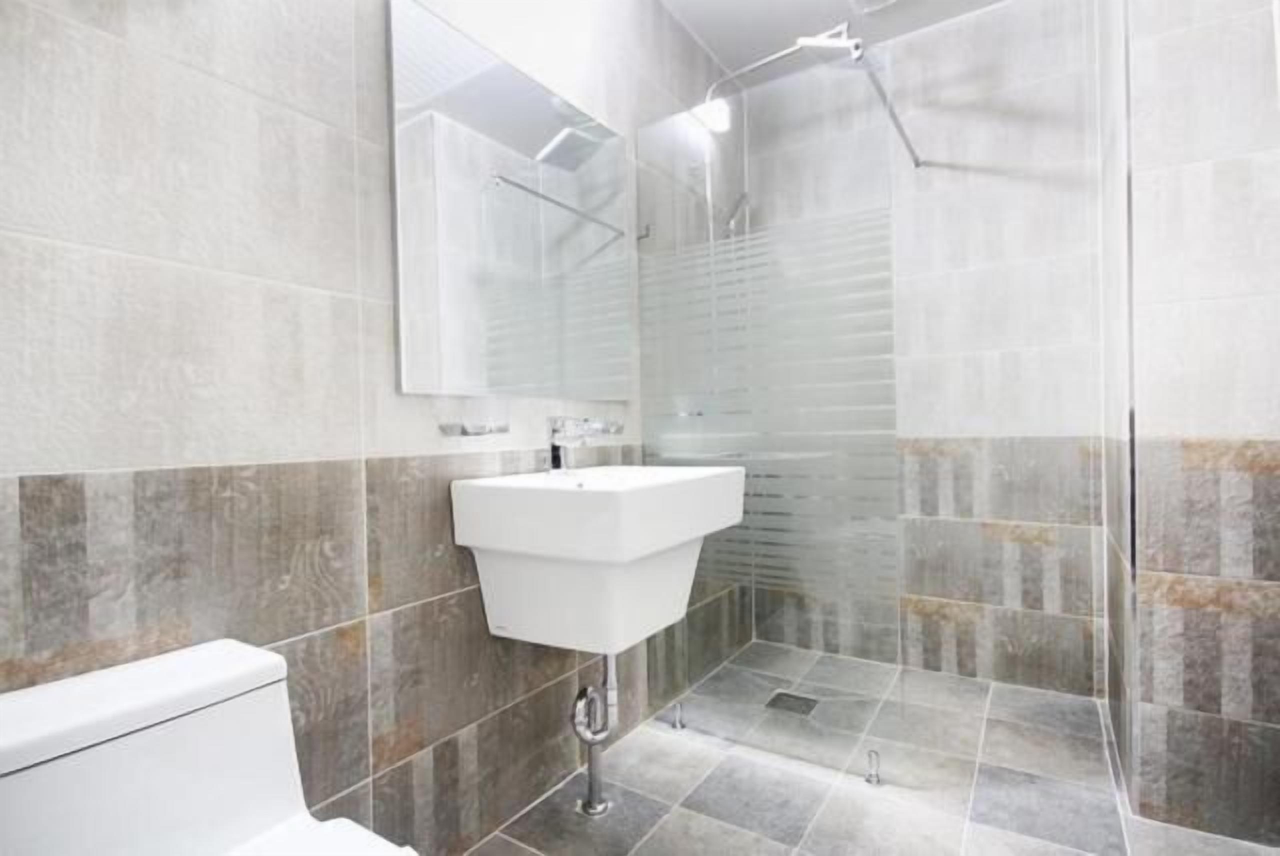 A modern bathroom with a white sink, a mirror, and a shower enclosure.
