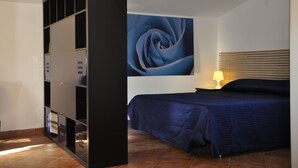 Une chambre à coucher comprenant un lit, un meuble de rangement fixé au mur et un grand tableau abstrait.