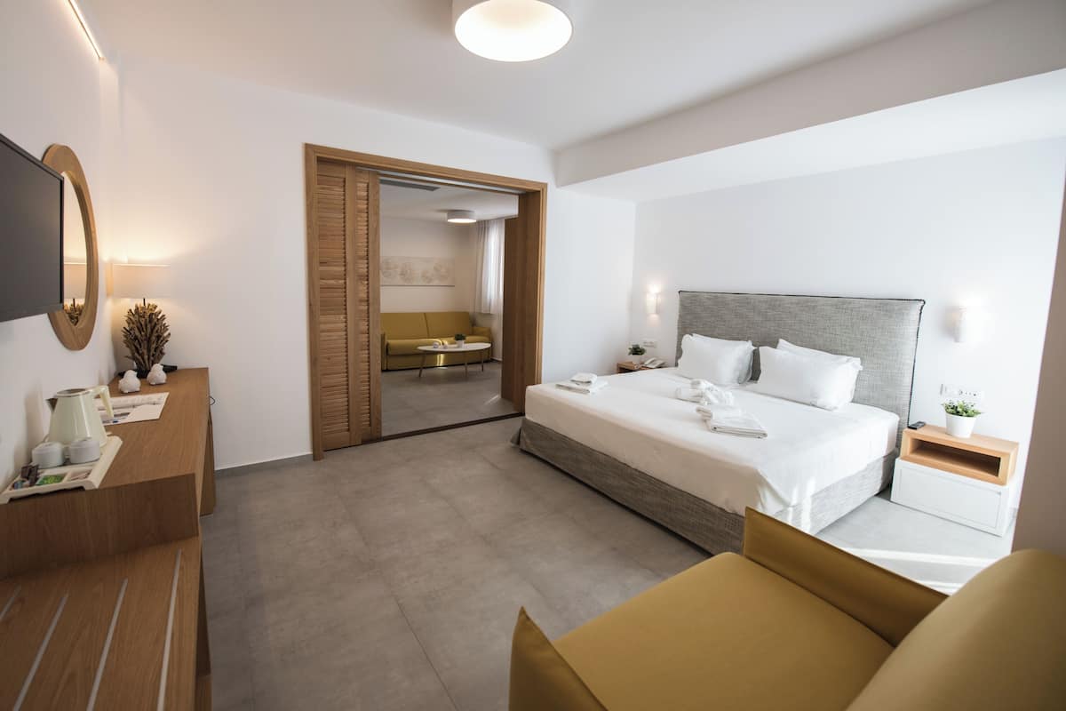 Une chambre d’hôtel moderne avec un grand lit, des tables de chevet, une télévision et un canapé.