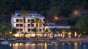 A multi-story hotel with balconies, a pool area, and a waterfront view.