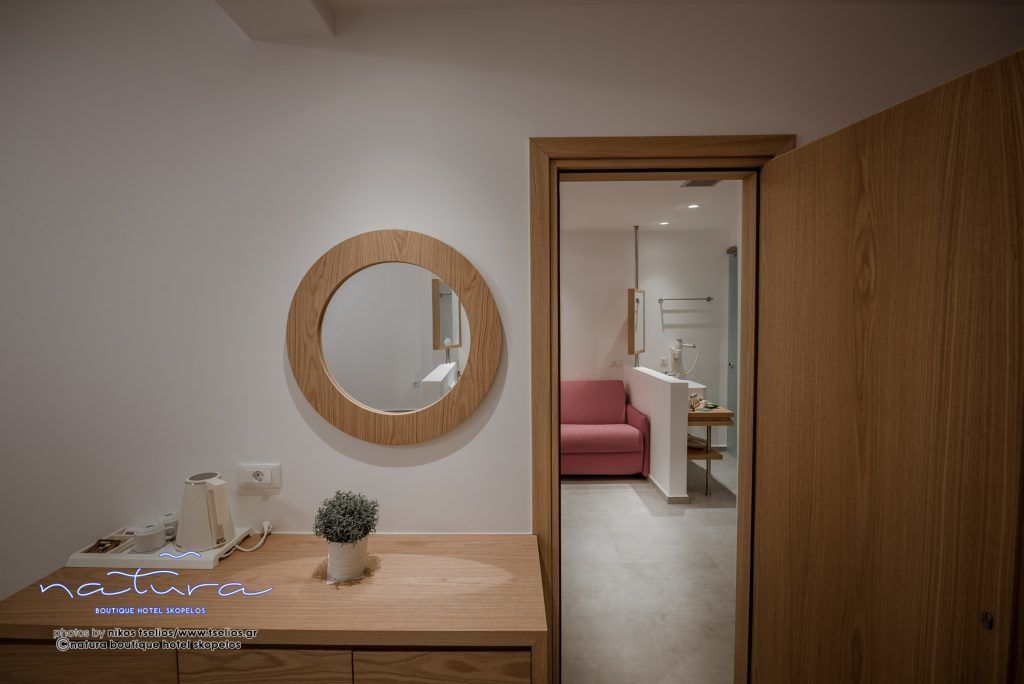 A modern bathroom with a wooden vanity, a round mirror, and a potted plant.