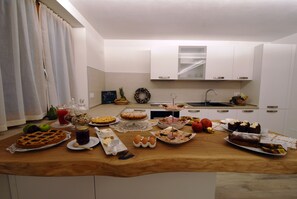 A kitchen with a wooden countertop filled with various food items and a white cabinet above. - Bike Bed&Breakfast Mille Pini (Baselga di Pine)