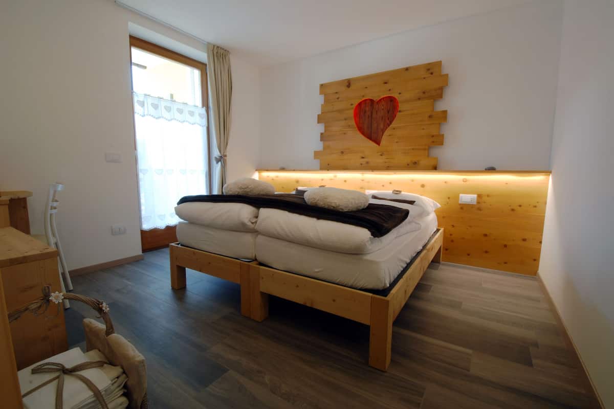 A bedroom with a wooden bed, a headboard with a heart design, and a window with curtains.