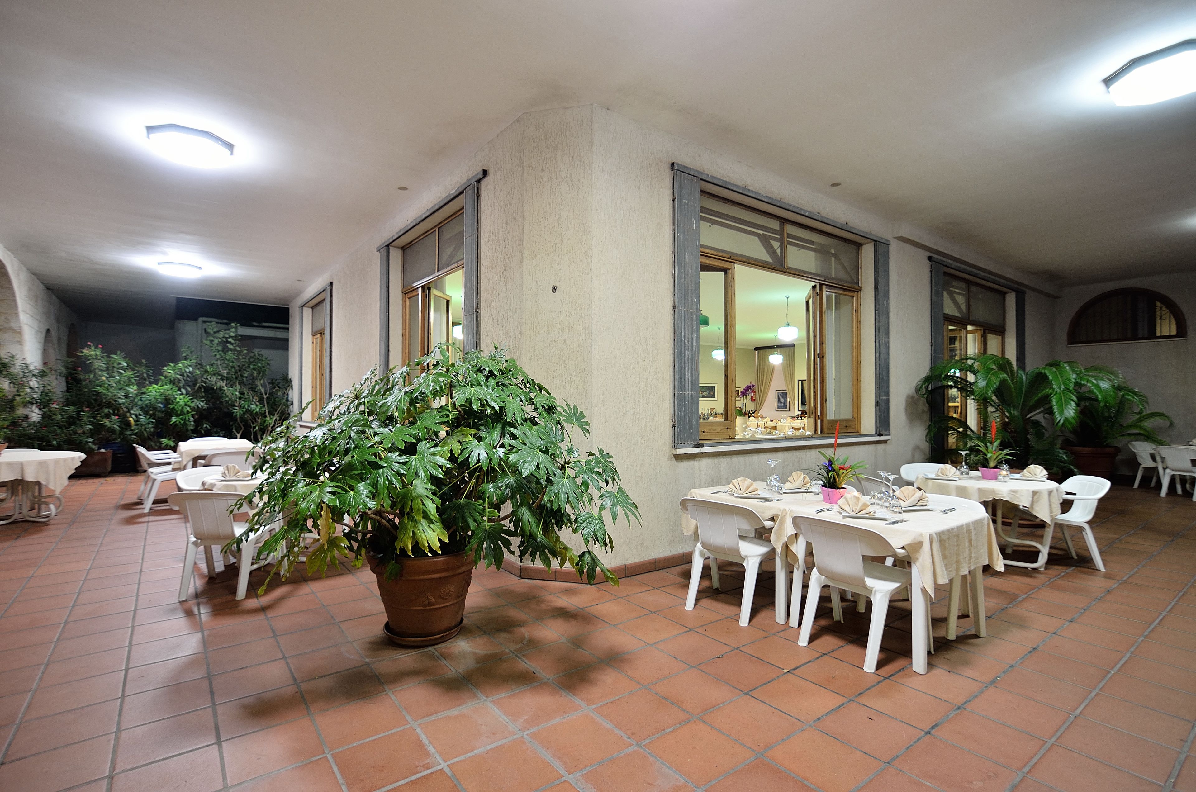 A restaurant with indoor seating, potted plants, and a tiled floor.