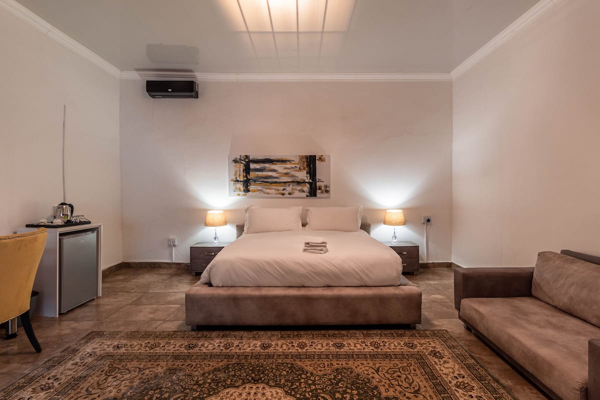 Un dormitorio con cama, lámparas de noche, un escritorio, una silla y una alfombra.