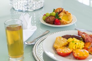 Una mesa de desayuno con un plato de huevos, tomates y un pastel, además de una taza de té.