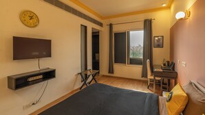 A hotel room with a bed, a desk, a chair, a TV, and a window with curtains. - The Hosteller Delhi (New Delhi)